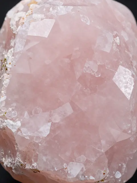 Full frame close-up of milky pink rose quartz showing natural crystal facets and soft mineral texture