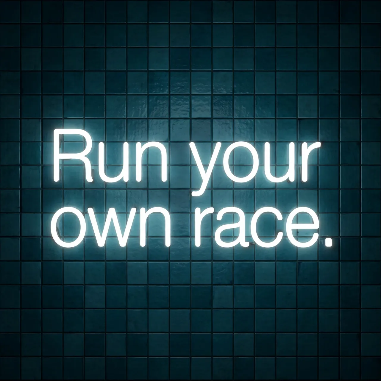 Glowing white neon sign reading "Run your own race." mounted on a dark teal tiled wall