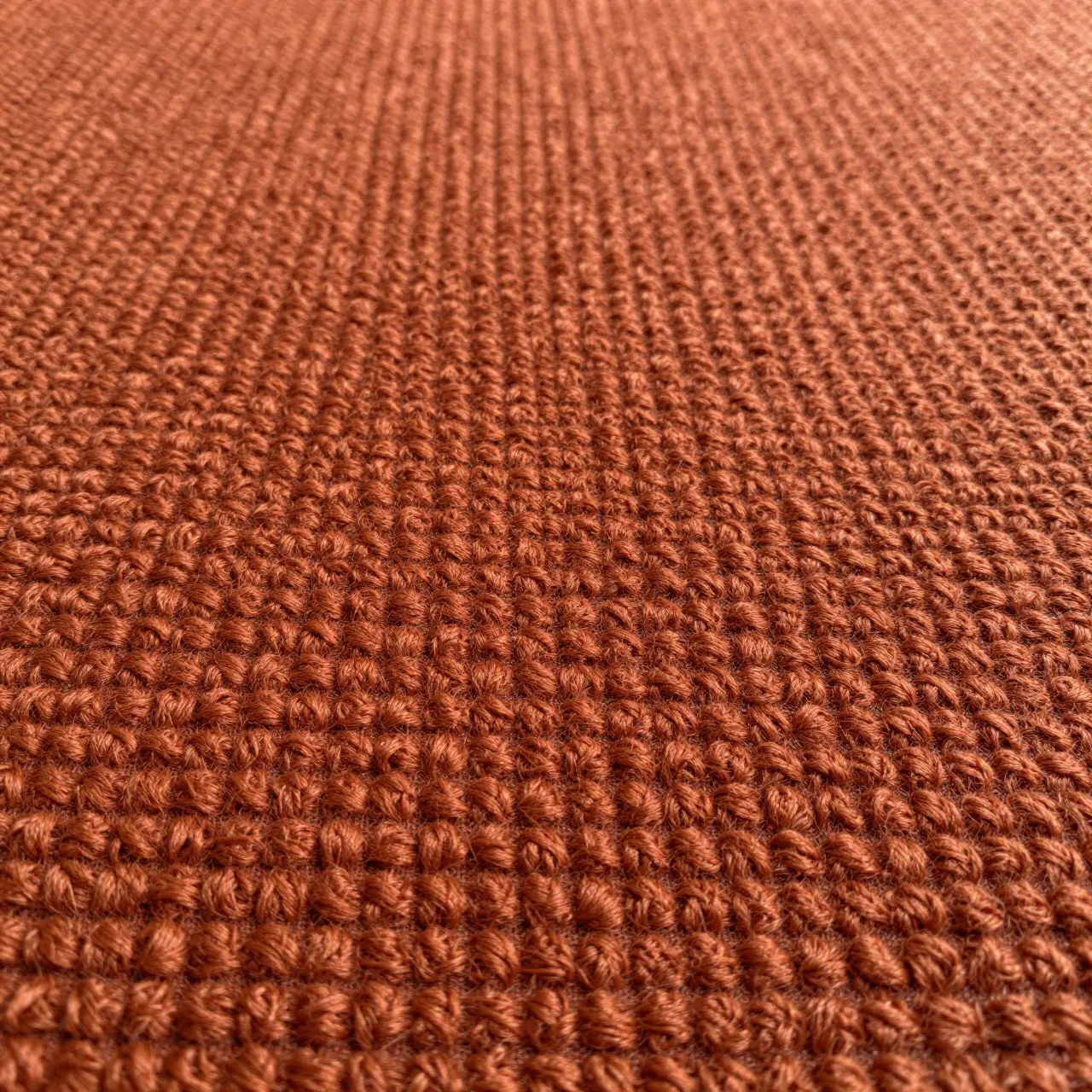 Full frame close-up of warm rust-orange boucle fabric with tight nubby woven loops