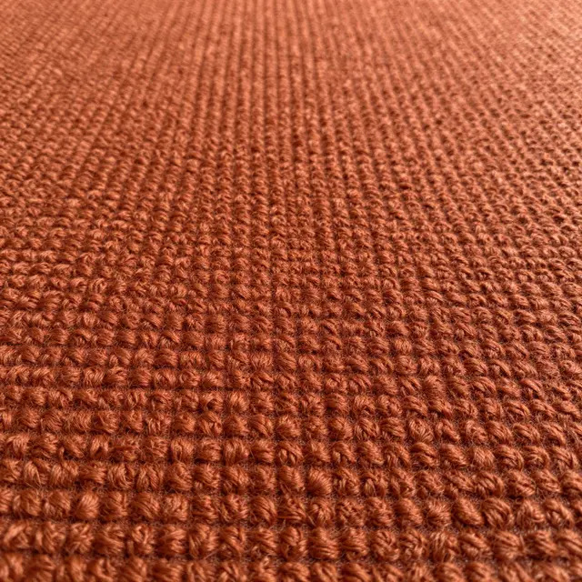 Full frame close-up of warm rust-orange boucle fabric with tight nubby woven loops