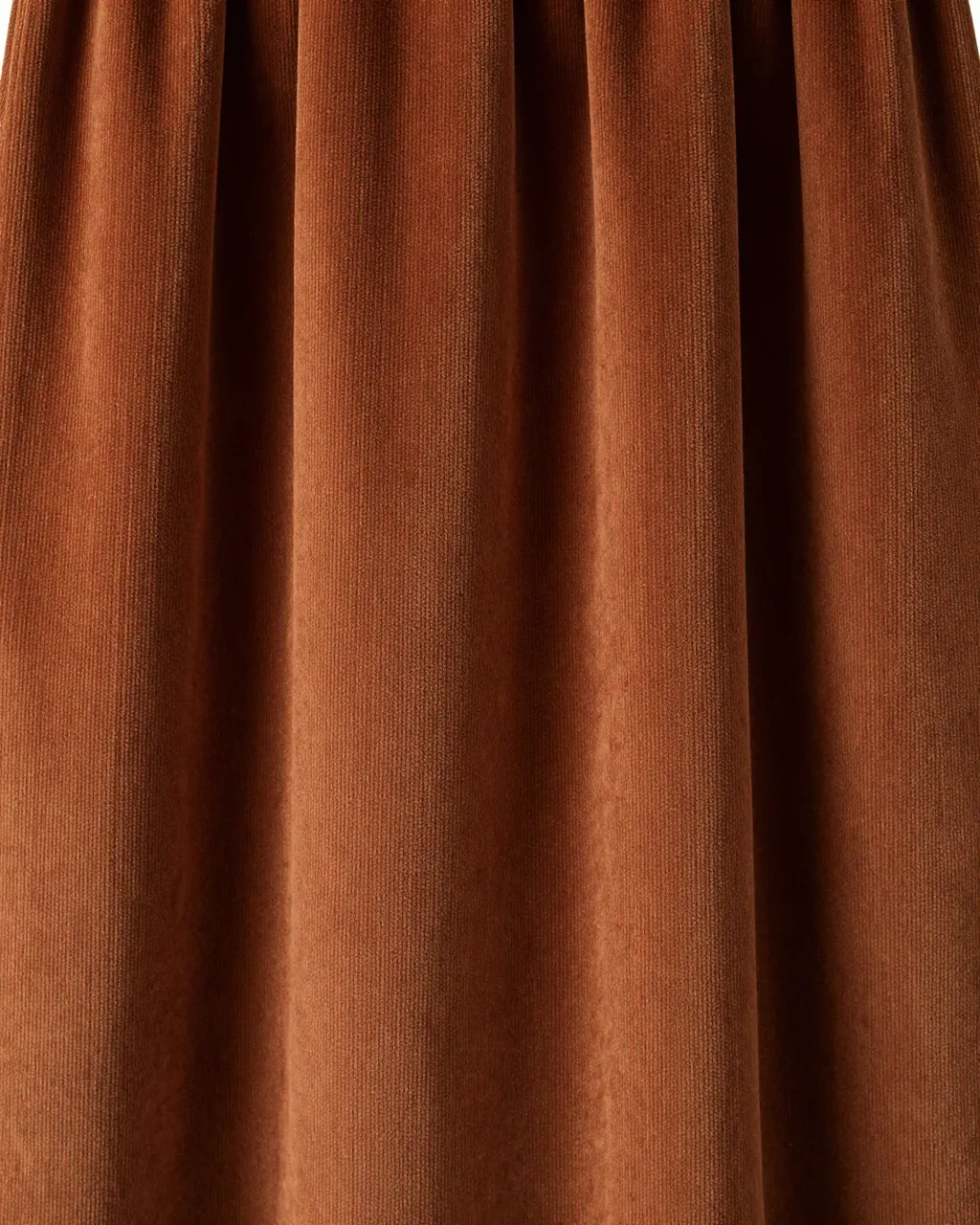 Full frame close-up of draped wide-wale rust corduroy lit by soft side lighting