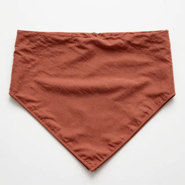A folded rust brown cotton bandana lies flat on a plain white surface.