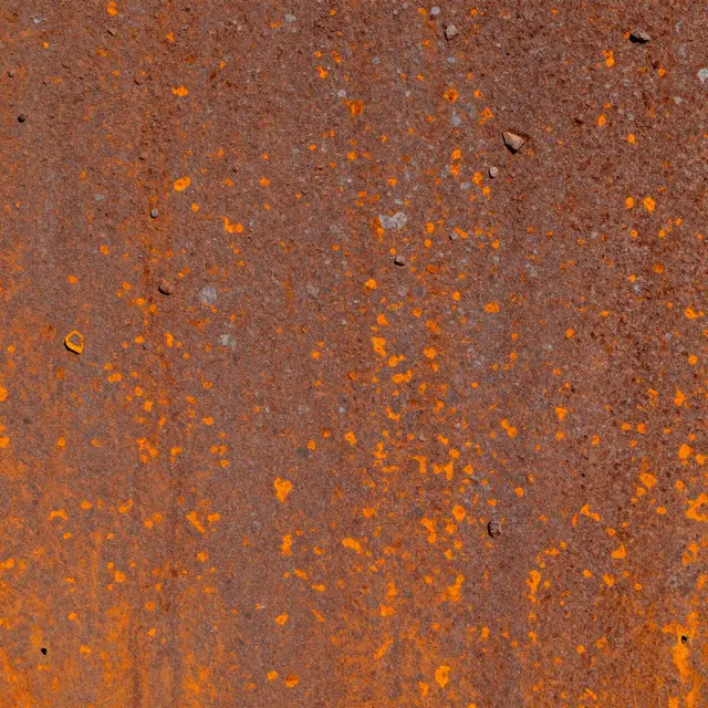 Full frame close-up of pitted rusted steel with flaking orange oxide scale and small embedded particles