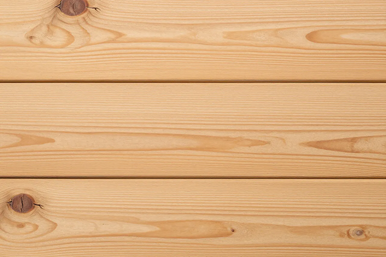 Full frame top view of light rustic oak planks with natural grain and dark knots under even lighting