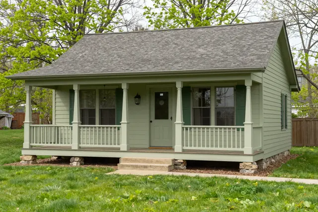 Sage green craftsman bungalow with a covered front porch set on a fresh spring lawn