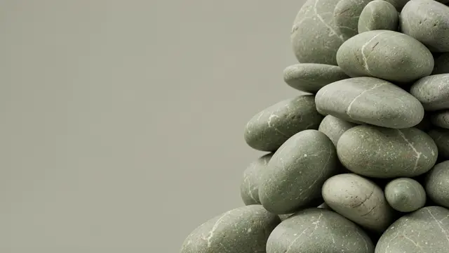 Stacked smooth sage and stone pebbles sit along the right edge of the frame, leaving empty copy space on the left