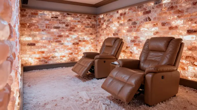 Reclining leather lounge chairs sit in an enclosed halotherapy room lined with glowing pink salt walls