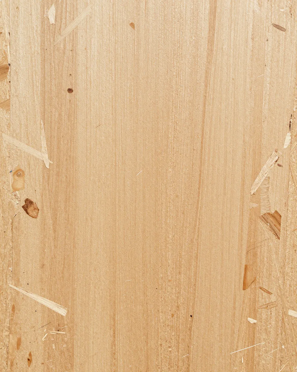 Full frame close-up of a smooth sanded tan particle board surface with embedded wood chips