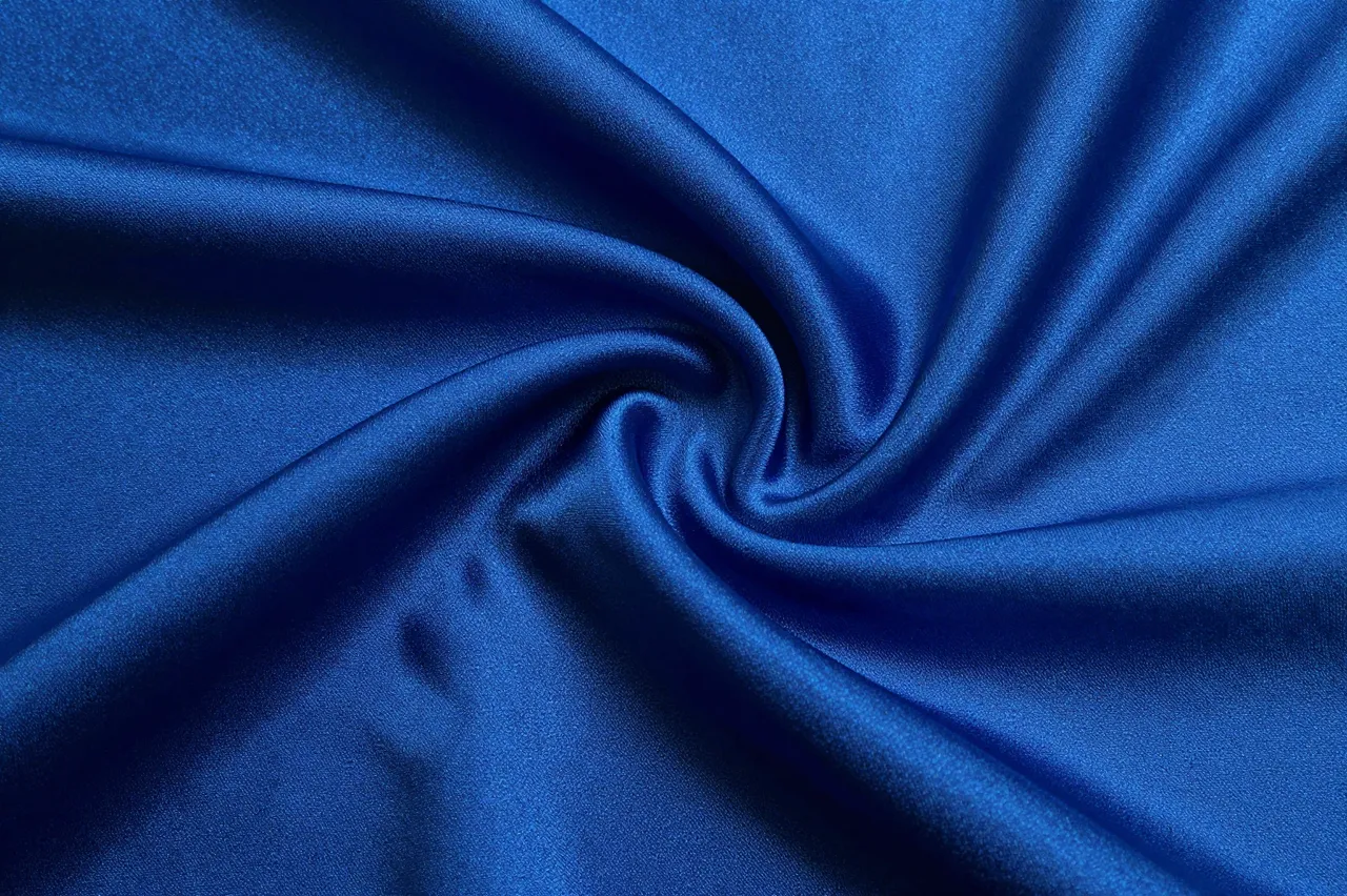 Twisted close-up of sapphire blue silk fabric with a soft liquid sheen