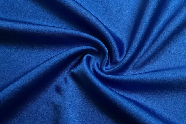Twisted close-up of sapphire blue silk fabric with a soft liquid sheen