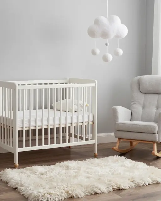 Minimalist scandi nursery with white crib, gray rocking chair, fluffy rug and hanging cloud mobile