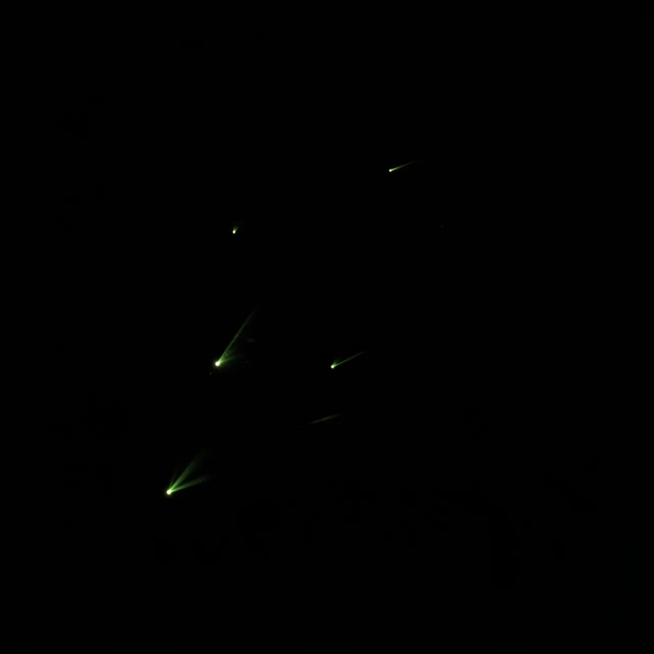 Faint green glowing points with soft light trails rest against a solid pure black background