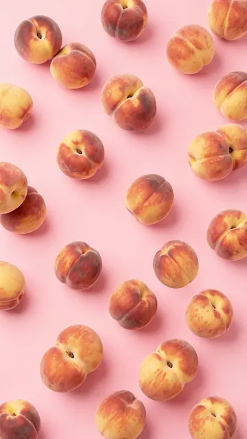 Ripe fuzzy peaches scattered evenly across a smooth solid pastel pink background