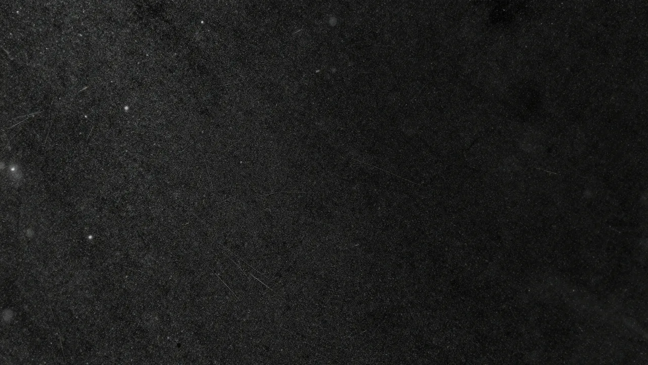 Close-up full frame of dust specks and fine scratches across a dark black glass surface