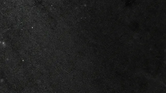 Close-up full frame of dust specks and fine scratches across a dark black glass surface