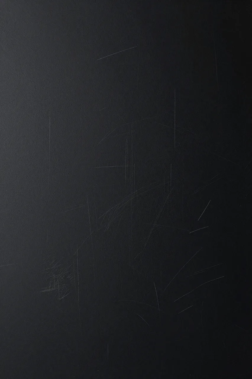 Matte black surface with faint thin chalky white scuff marks and subtle side lighting gradient