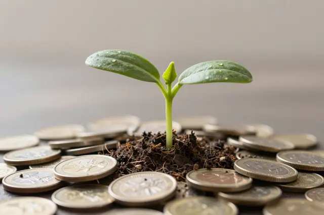 A young green seedling with water droplets grows from soil surrounded by scattered metal coins