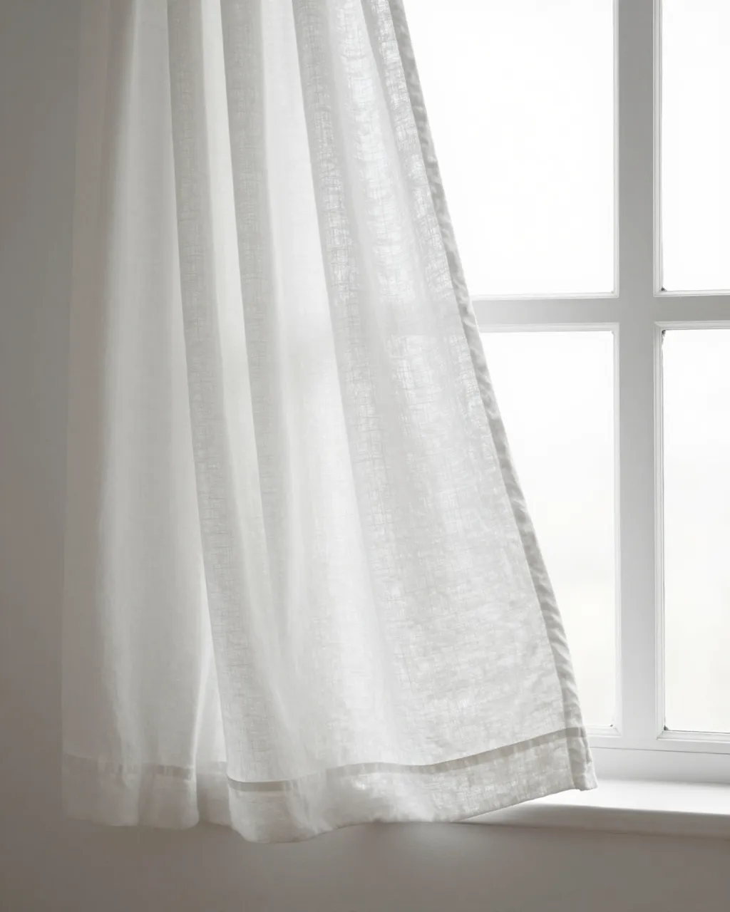 Soft white linen curtain hangs beside a bright paned window, catching gentle diffused light.