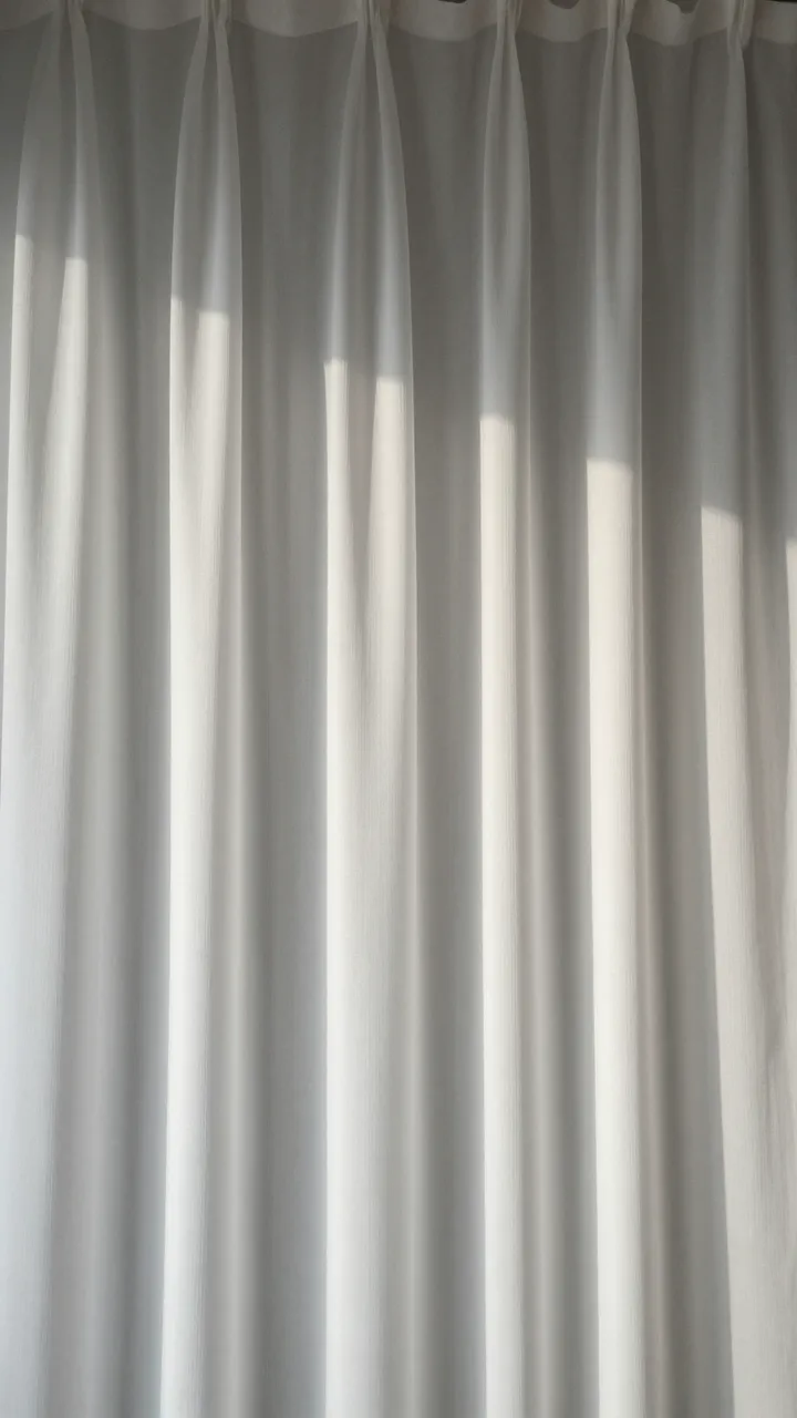Soft backlit sheer white draped curtain provides neutral vertical copy space