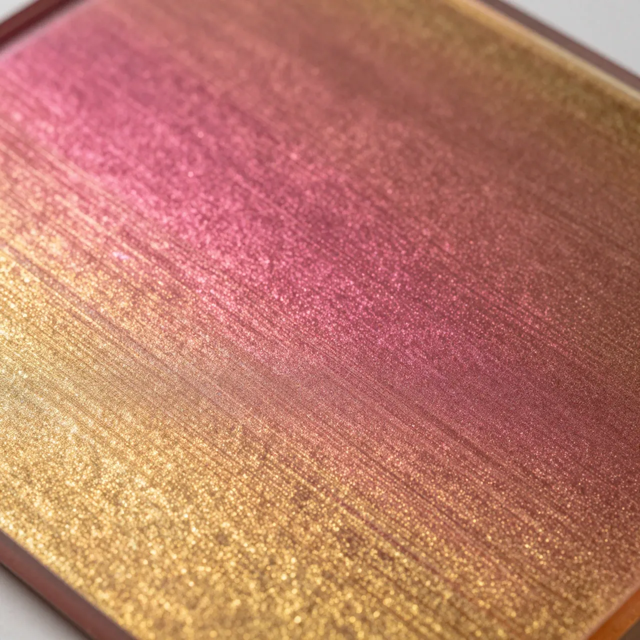 Full frame close-up of a shimmering textured surface blending magenta and gold with soft glittering highlights