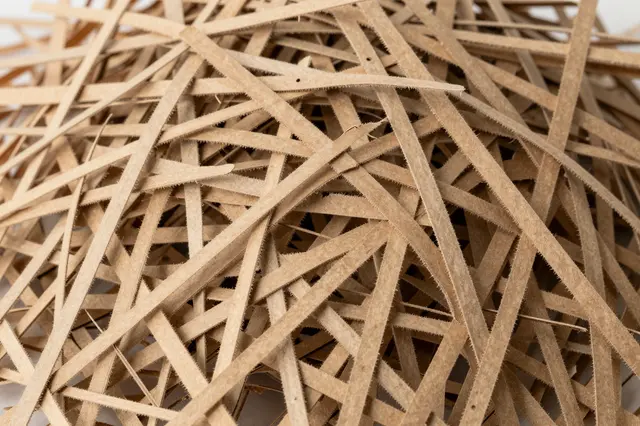 Top view of a dense heap of thin shredded kraft paper strands filling the frame