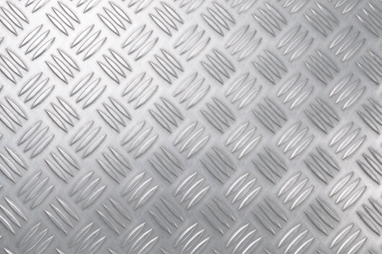Full frame close-up of uniform raised diamond pattern silver aluminum tread plate with even lighting