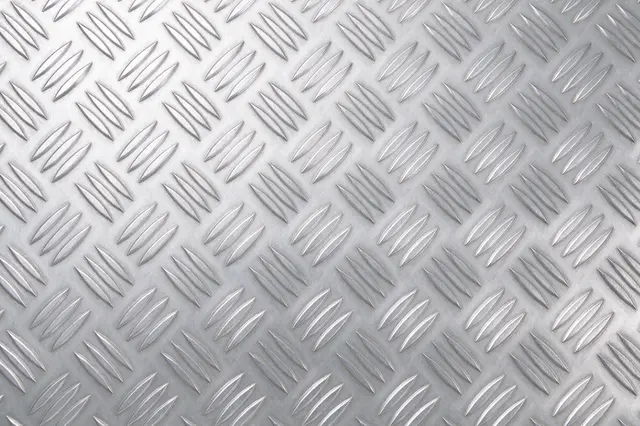 Full frame close-up of uniform raised diamond pattern silver aluminum tread plate with even lighting