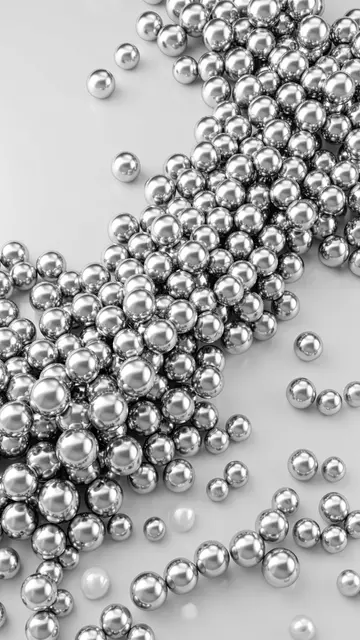 Shiny chrome silver spheres rest scattered across a smooth pale gray surface