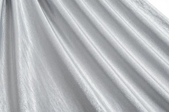 Close-up of draped silver moire taffeta fabric with soft watery ripple sheen under even light