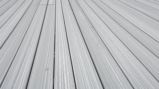 Close-up top view of parallel silver weathered teak decking boards under overcast light