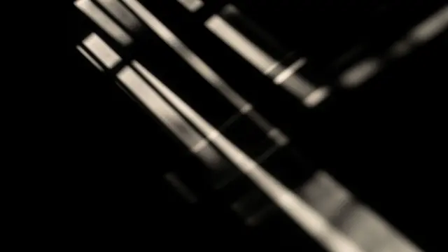 Soft parallel slanted warm light beams cast across a solid pure black background