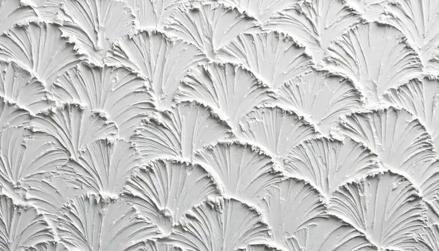 Full frame close-up of white slap brush ceiling texture with overlapping fan-shaped drywall mud ridges