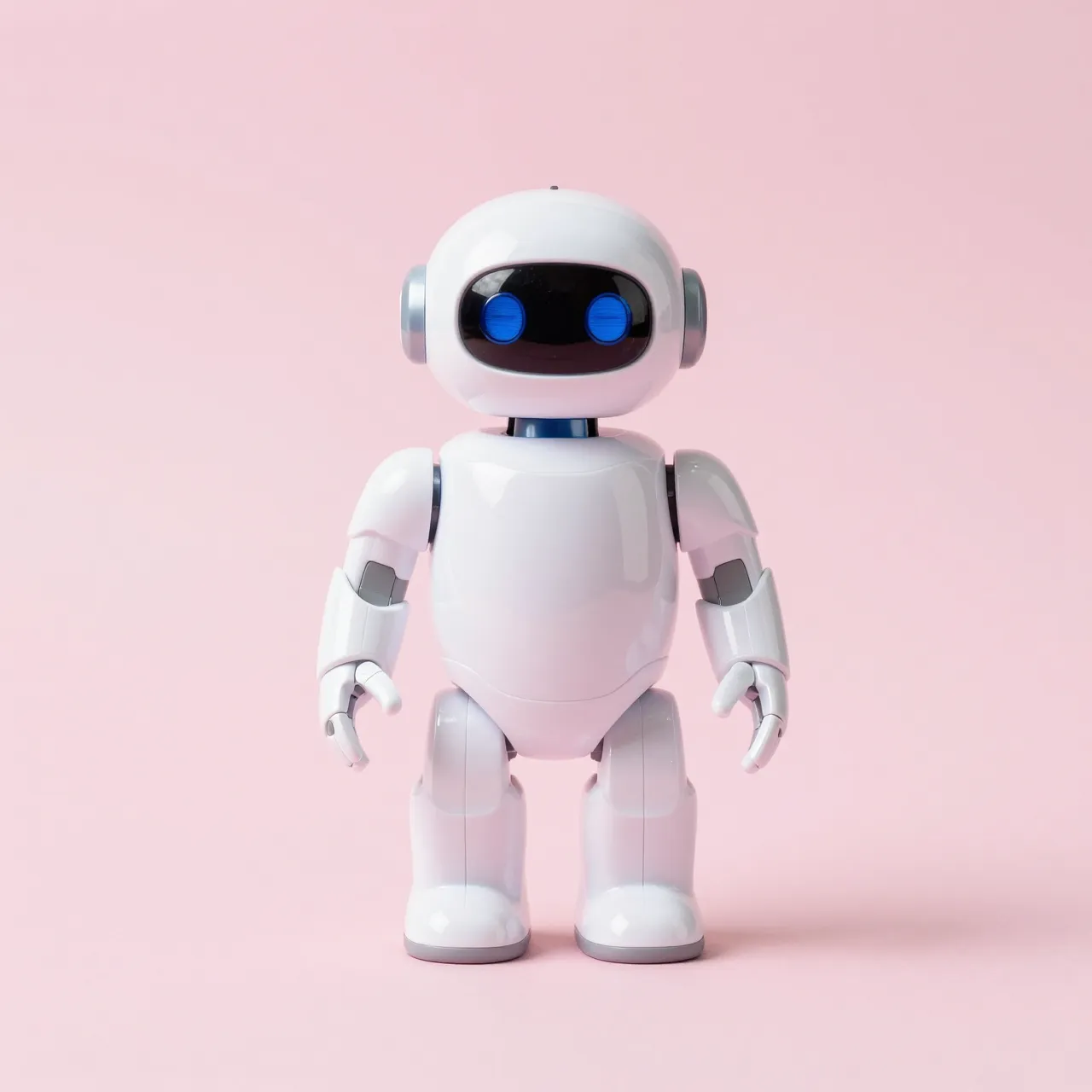 Glossy white toy robot with round blue eyes stands centered on a solid pastel pink background