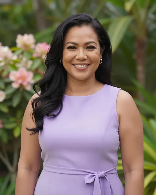 A smiling Pacific Islander woman in a lilac dress stands in a sunny flowering garden.