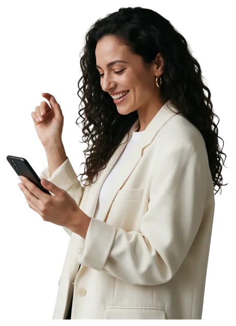 A woman in an oversized cream blazer smiles while looking down at the smartphone she holds.