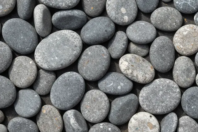 Top view of a dense, overlapping collection of smooth rounded gray river pebbles