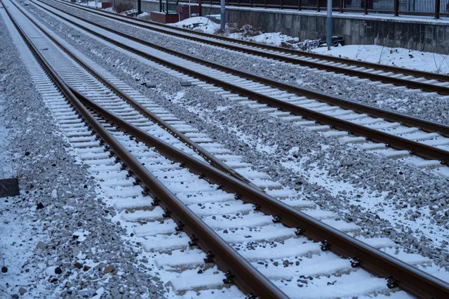 Multiple snow-dusted railway tracks stretch into the distance under cool dusk lighting