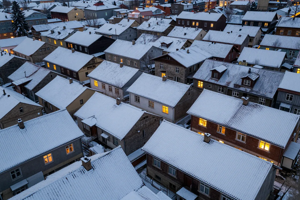 Aerial view of snow-covered old town rooftops with glowing warm windows at twilight