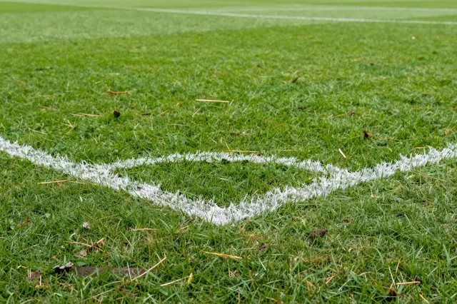 Low angle close up of worn grass around the white penalty spot markings on a soccer pitch