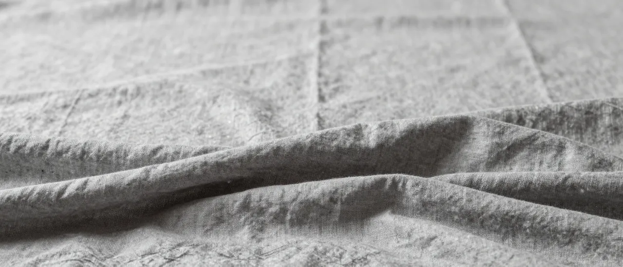 Gentle folded soft gray linen with gathered lower folds and empty blurred space above