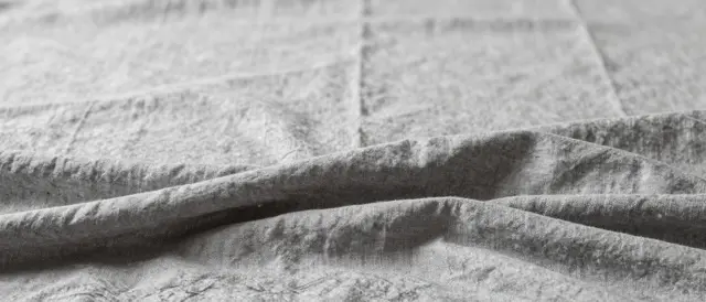 Gentle folded soft gray linen with gathered lower folds and empty blurred space above