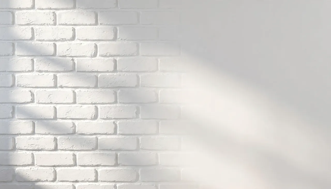 Painted white brick wall with soft left-side lighting and large blank right copy space