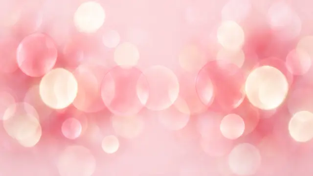 Dreamy defocused rose and cream bokeh circles over a light pink base background