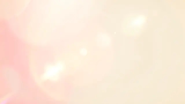 Warm soft pink and golden light leak bokeh flares drift over a pale cream background