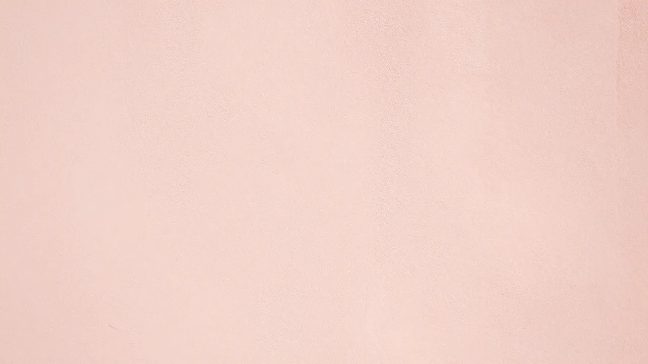 Smooth light pink plaster wall lit by soft warm morning sunlight