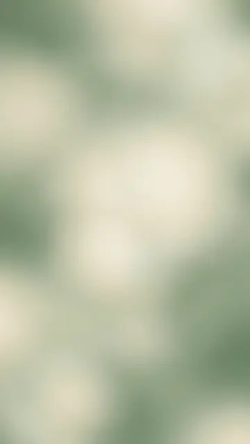 A smooth blurred vertical gradient of sage green and pale cream with soft grain and faint glowing highlights