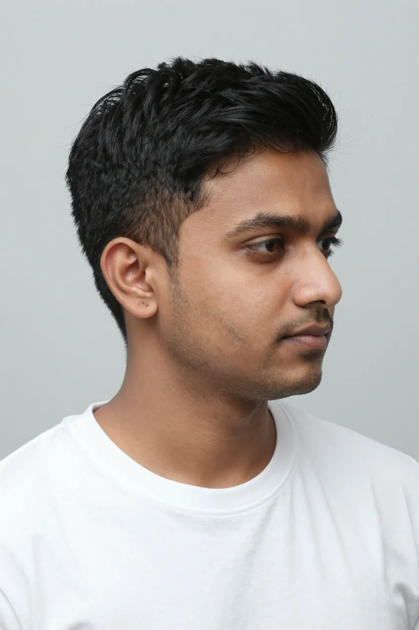 Three-quarter view portrait of a South Asian man in his thirties with a textured quiff, wearing a plain white t-shirt