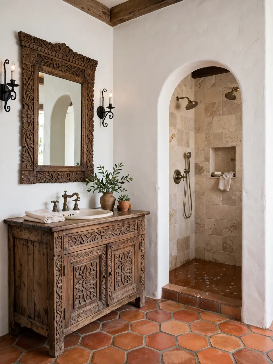 A sunlit Spanish colonial bathroom with carved wood vanity, arched shower and terracotta tile flooring