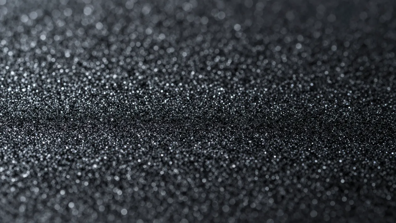 Close-up of fine black glitter sparkling softly under diffused light with gentle bokeh highlights