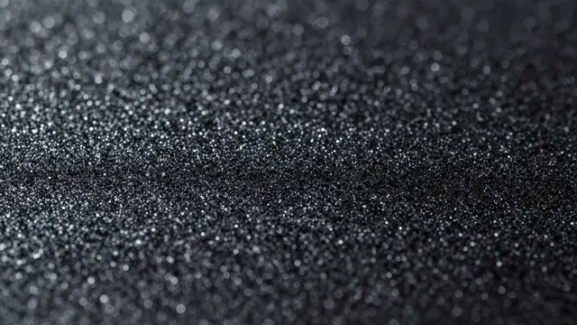 Close-up of fine black glitter sparkling softly under diffused light with gentle bokeh highlights